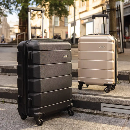Two suitcases, one black and one beige, on a city street.