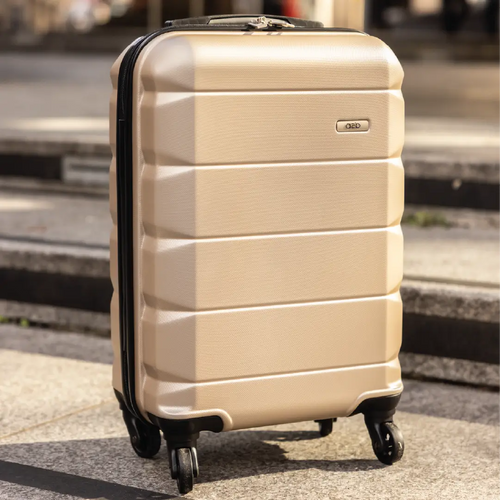 Beige suitcase with black wheels on a pavement