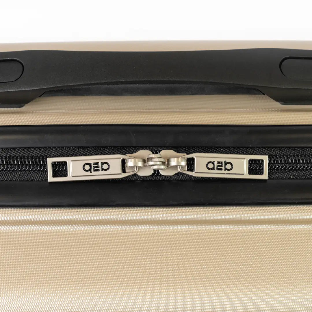 Close-up of a beige suitcase with a black handle and visible brand logo.