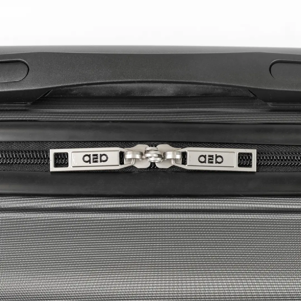 Close-up of a gray suitcase with a zipper and 'QED' branding.