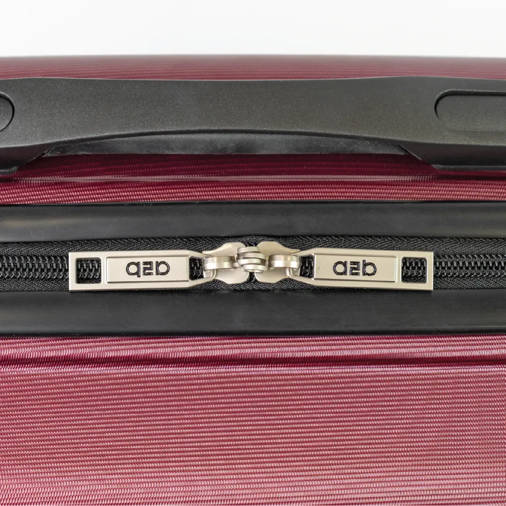 Close-up of a red suitcase zipper with branding on a white background