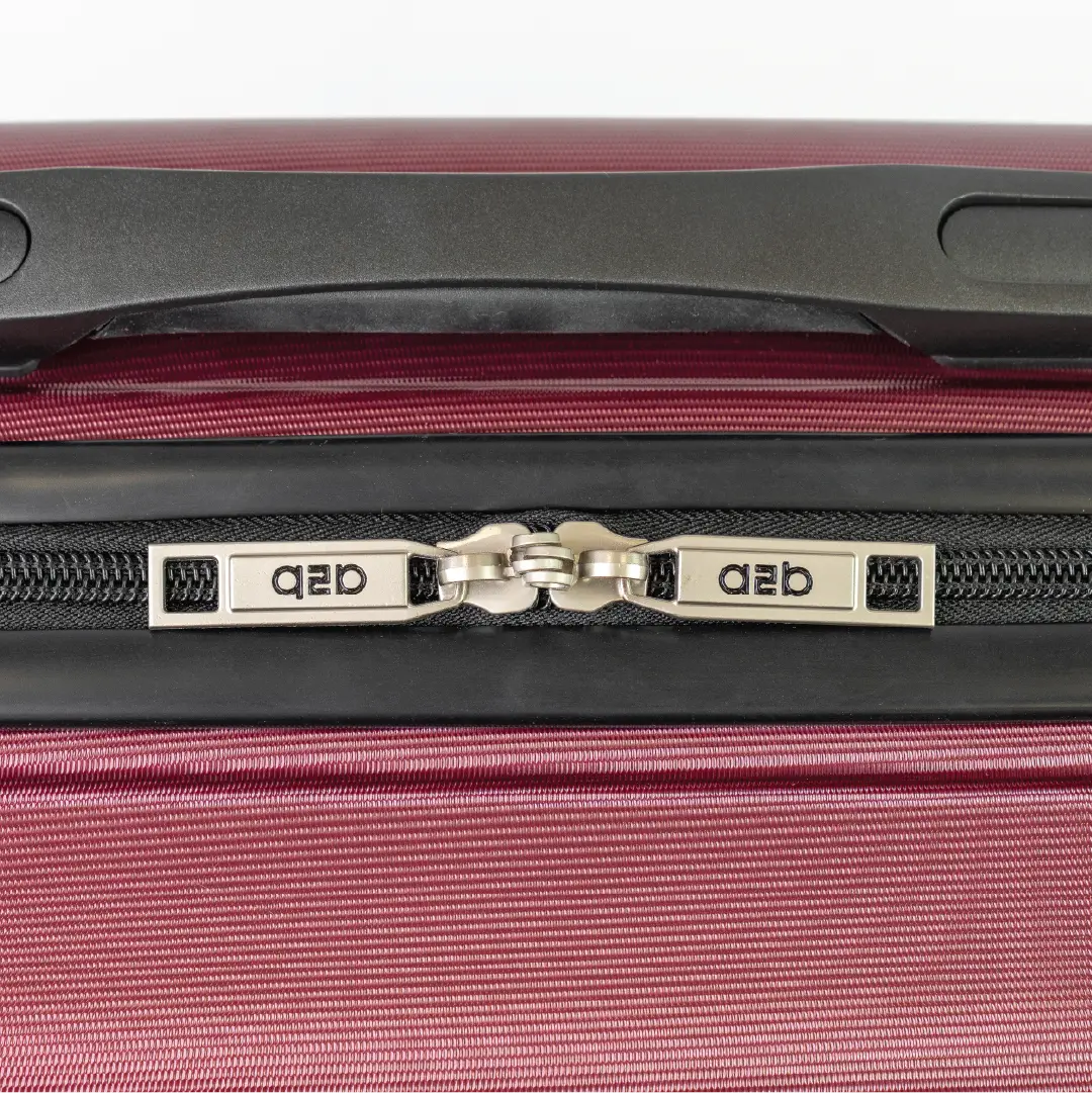 Close-up of a red suitcase zipper with branding on a white background