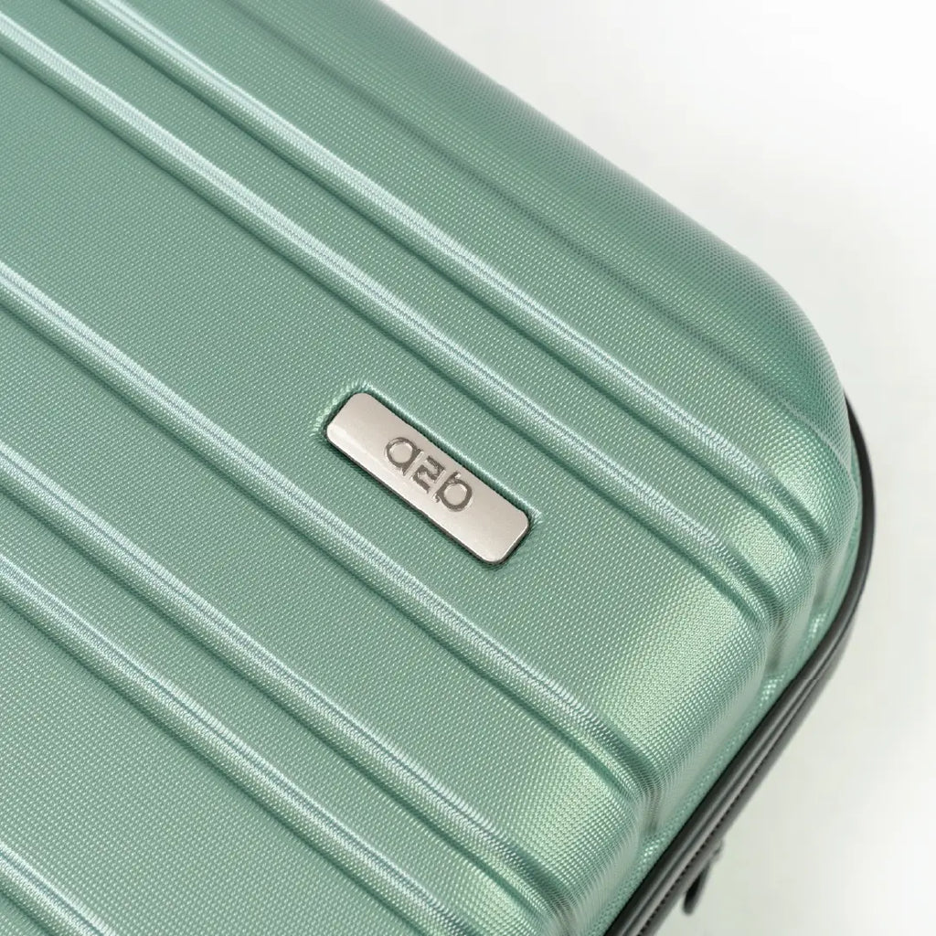 Mint green suitcase with a brand logo on a light gray background