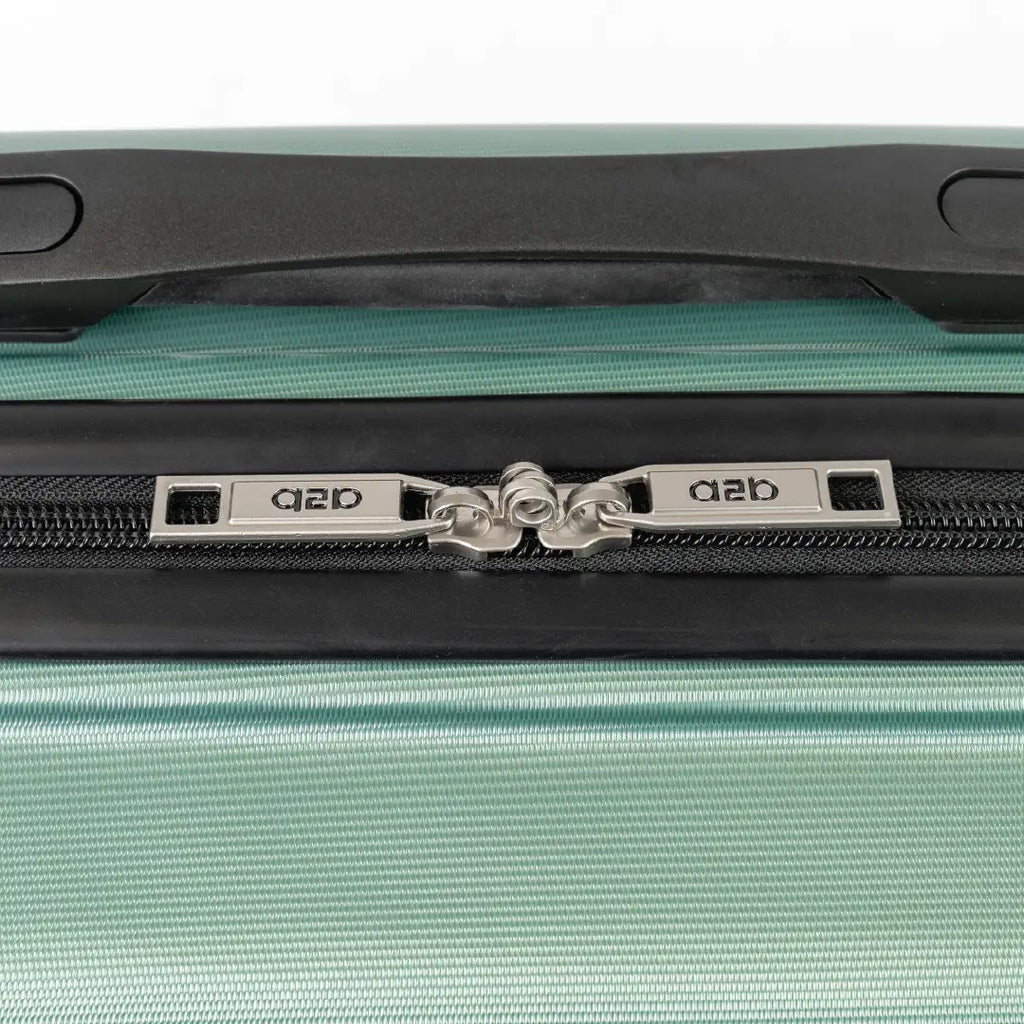 Close-up of a green suitcase zipper with a brand logo on a white background