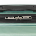 Close-up of a green suitcase zipper with a brand logo on a white background