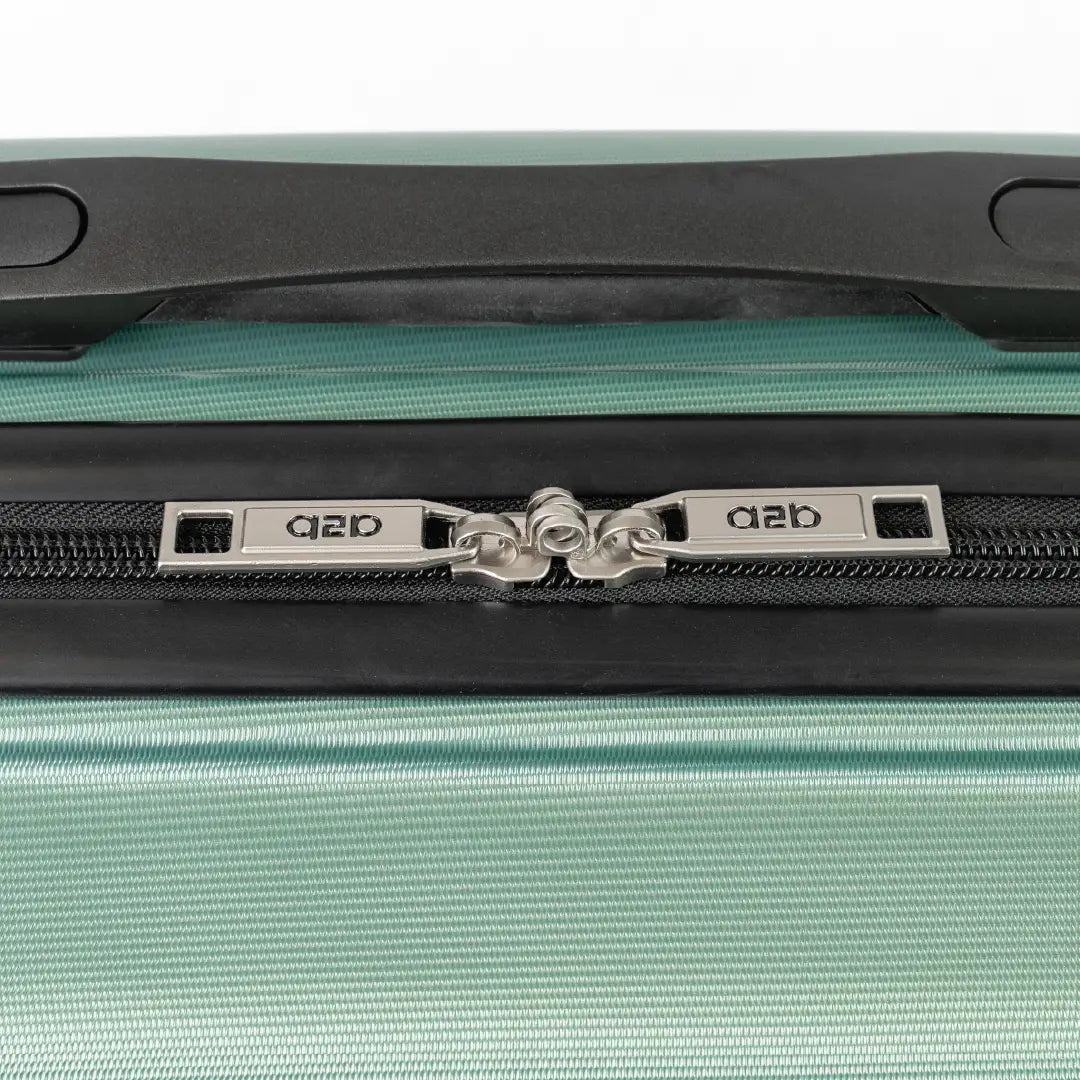 Close-up of a green suitcase zipper with a brand logo on a white background