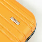 Close-up of a yellow suitcase with a brand logo on a light gray background