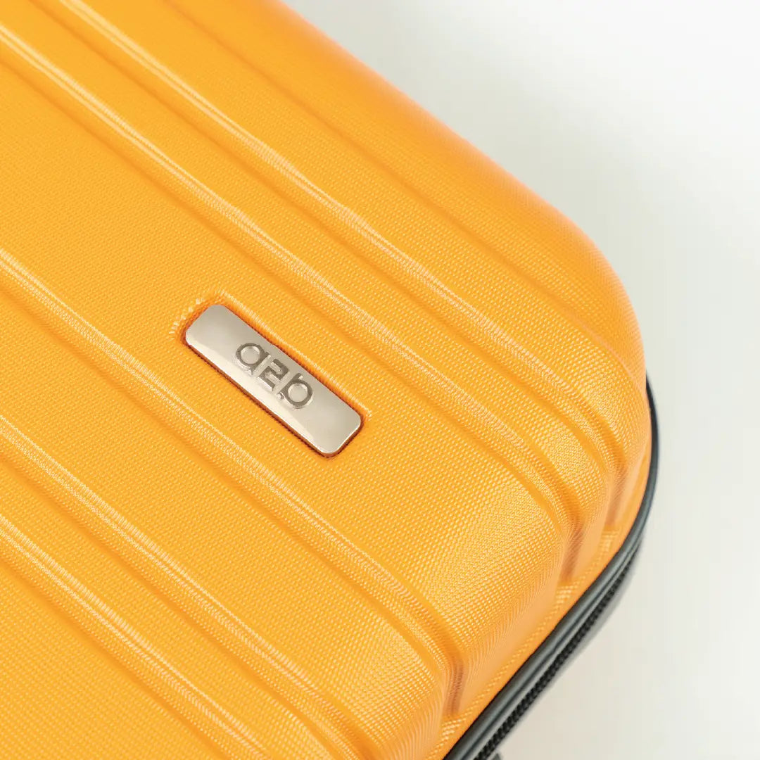 Close-up of a yellow suitcase with a brand logo on a light gray background