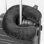 Gray travel neck pillow on a suitcase with a white background