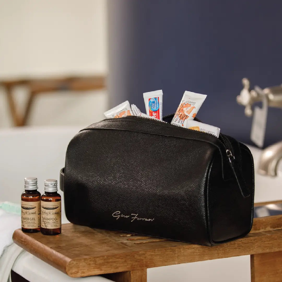 Black toiletry bag with personal care items on a wooden surface