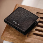 Black textured wallet with branding on a wooden surface