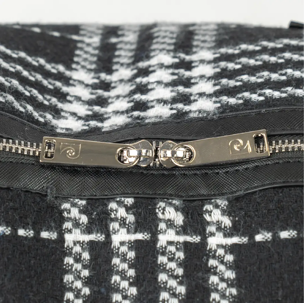 Close-up of a black and white patterned bag with a silver zipper and brand logo.