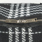 Close-up of a black and white patterned bag with a silver zipper and brand logo.