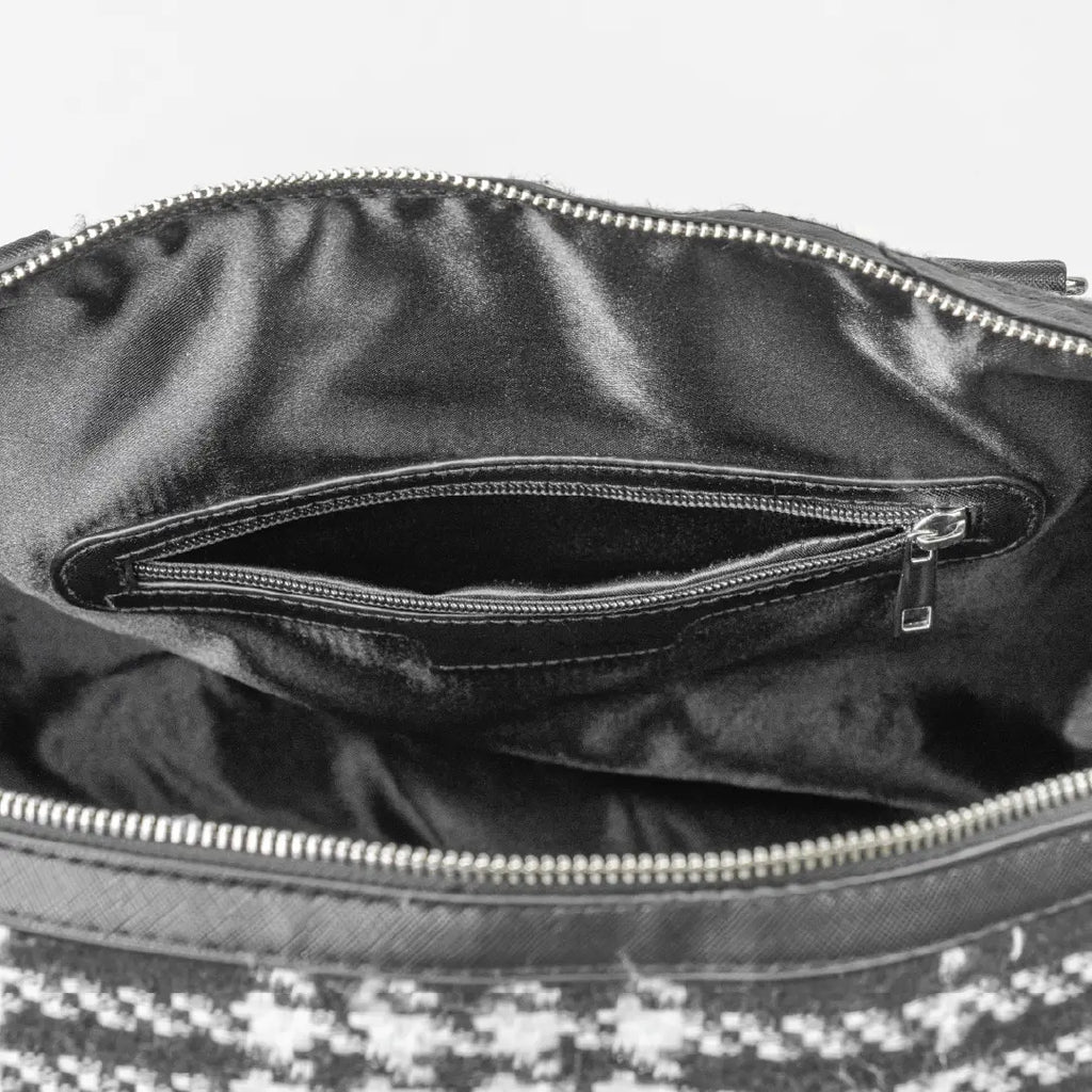 Close-up of a black leather handbag with a zipper, showing the interior.
