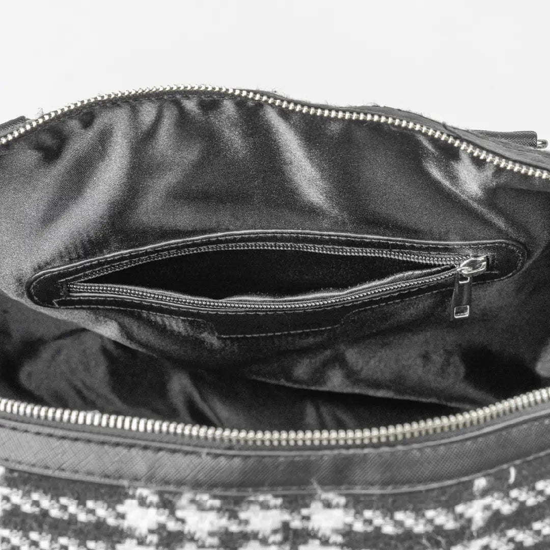 Close-up of a black leather handbag with a zipper, showing the interior.