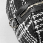 Close-up of a black and white patterned bag with a zipper and ring detail.