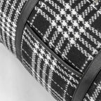 Close-up of a black and white checkered bag with a zipper on a light gray background