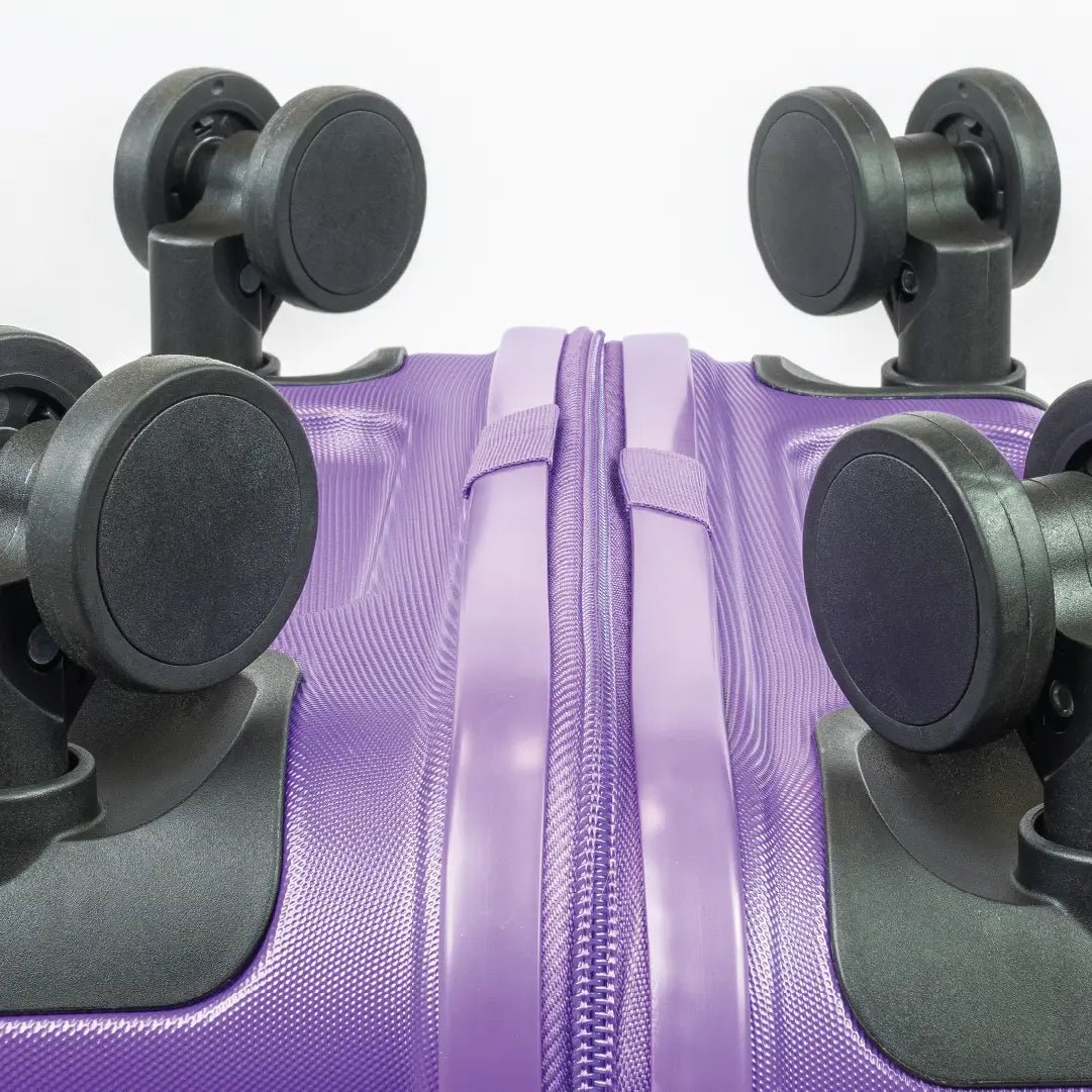 Close-up of a purple suitcase with black wheels on a white background