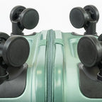 Close-up of a green suitcase with black wheels on a white background