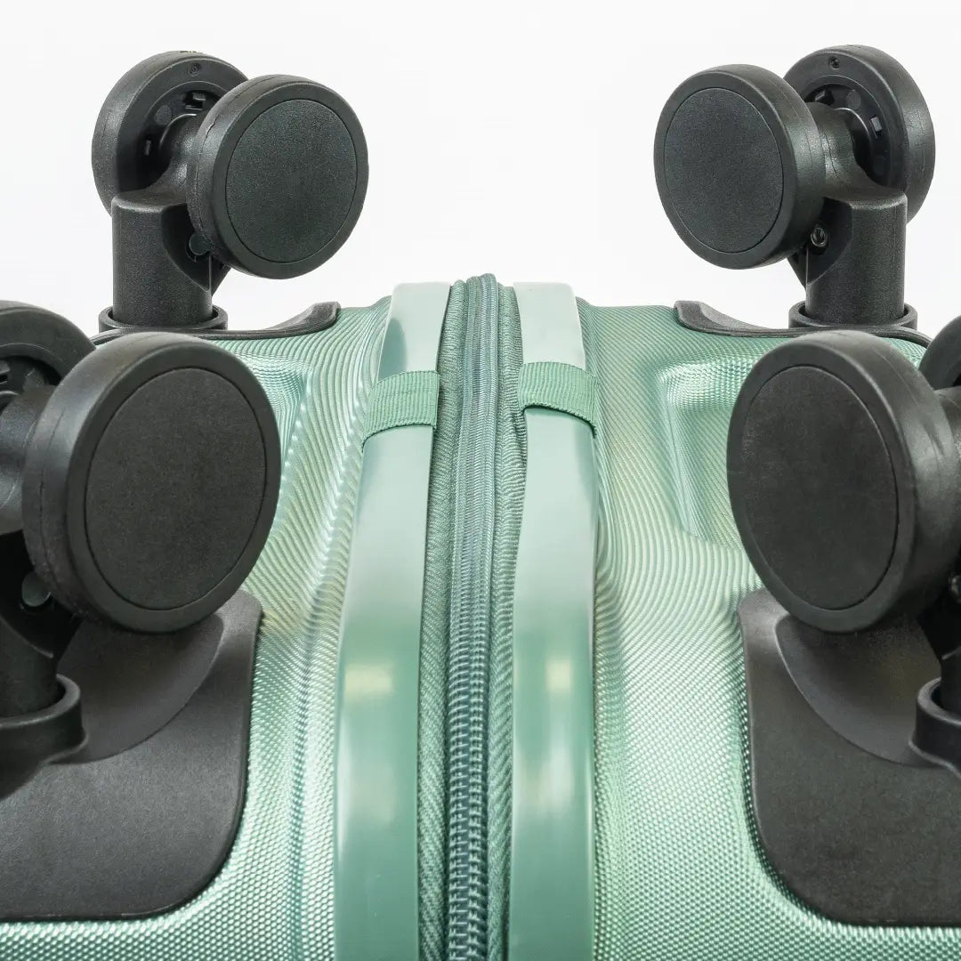 Close-up of a green suitcase with black wheels on a white background