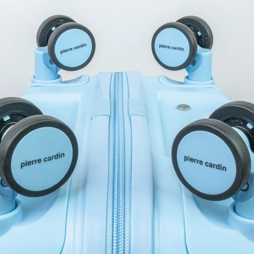 Light blue suitcase with 'Pierre Cardin' branding on wheels against a light gray background