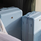 Two light blue suitcases with a visible brand logo on a bed.