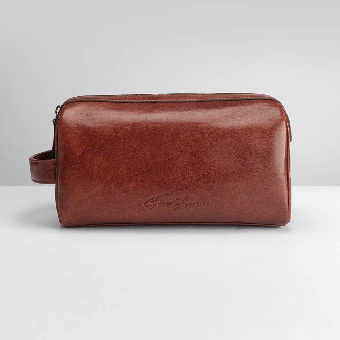 Brown leather toiletry bag on a light gray background