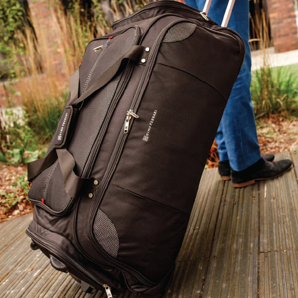 Black rolling suitcase with brand logo on a wooden surface outdoors