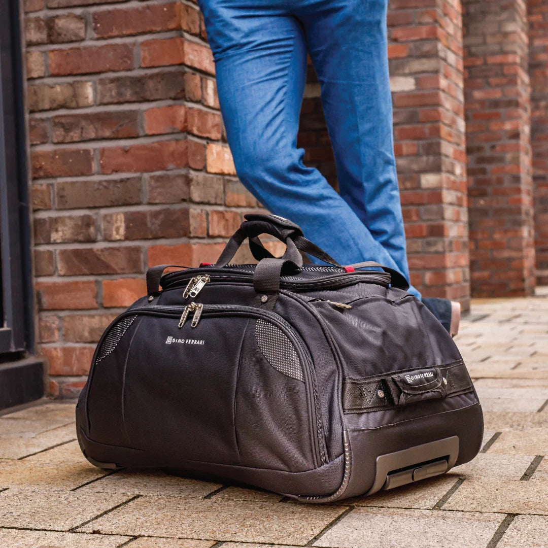 Black duffel bag on a stone pavement with a brick wall background