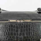 Leather-look textured bag with a pocket, handles and a silver zip with branding on it.
