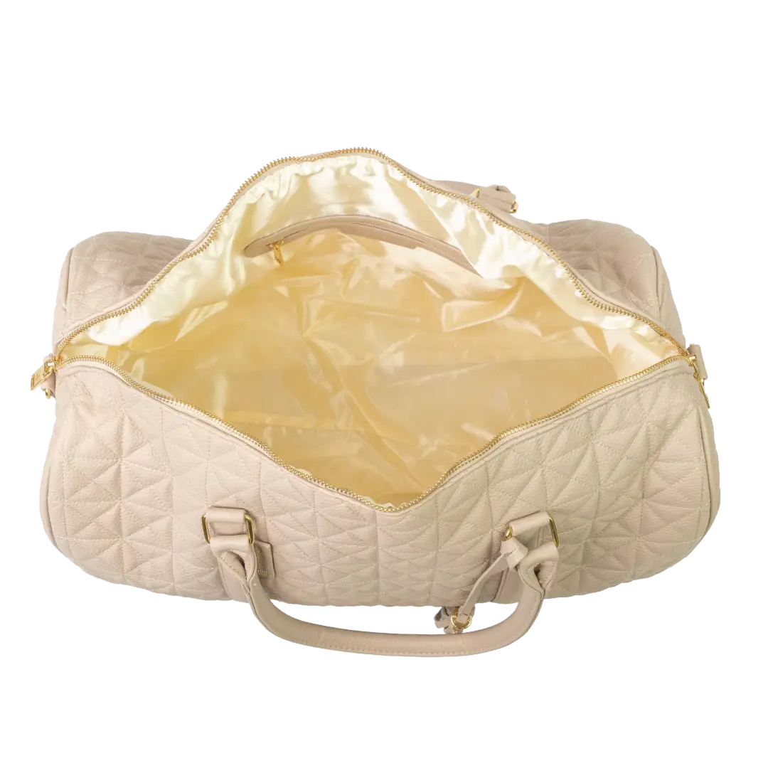 A close-up of a beige bag with cream interior, patterned stitching and a gold zip.