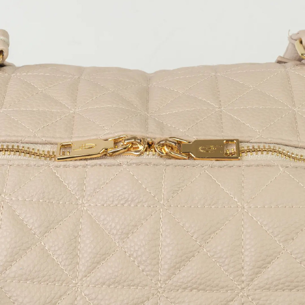 A close-up of a beige bag with patterned stitching and a gold zip.