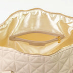 A close-up of a beige bag with cream interior, patterned stitching and a gold zip.