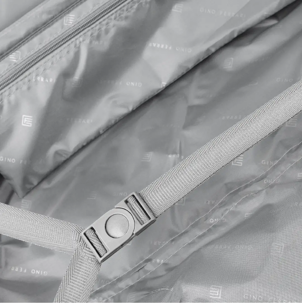 Close-up of a suitcase with a strap and buckle, featuring a brand logo.
