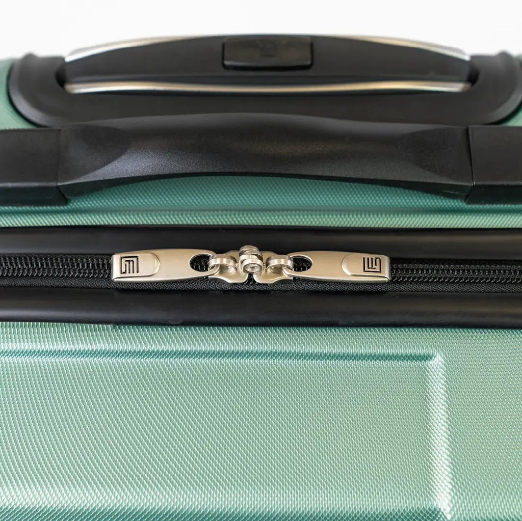 Close-up of a green suitcase with a black handle and zipper.
