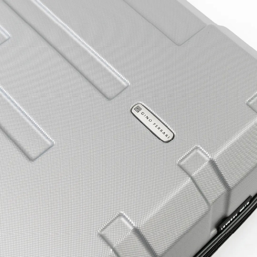 Close-up of a silver suitcase with a brand logo on a white background
