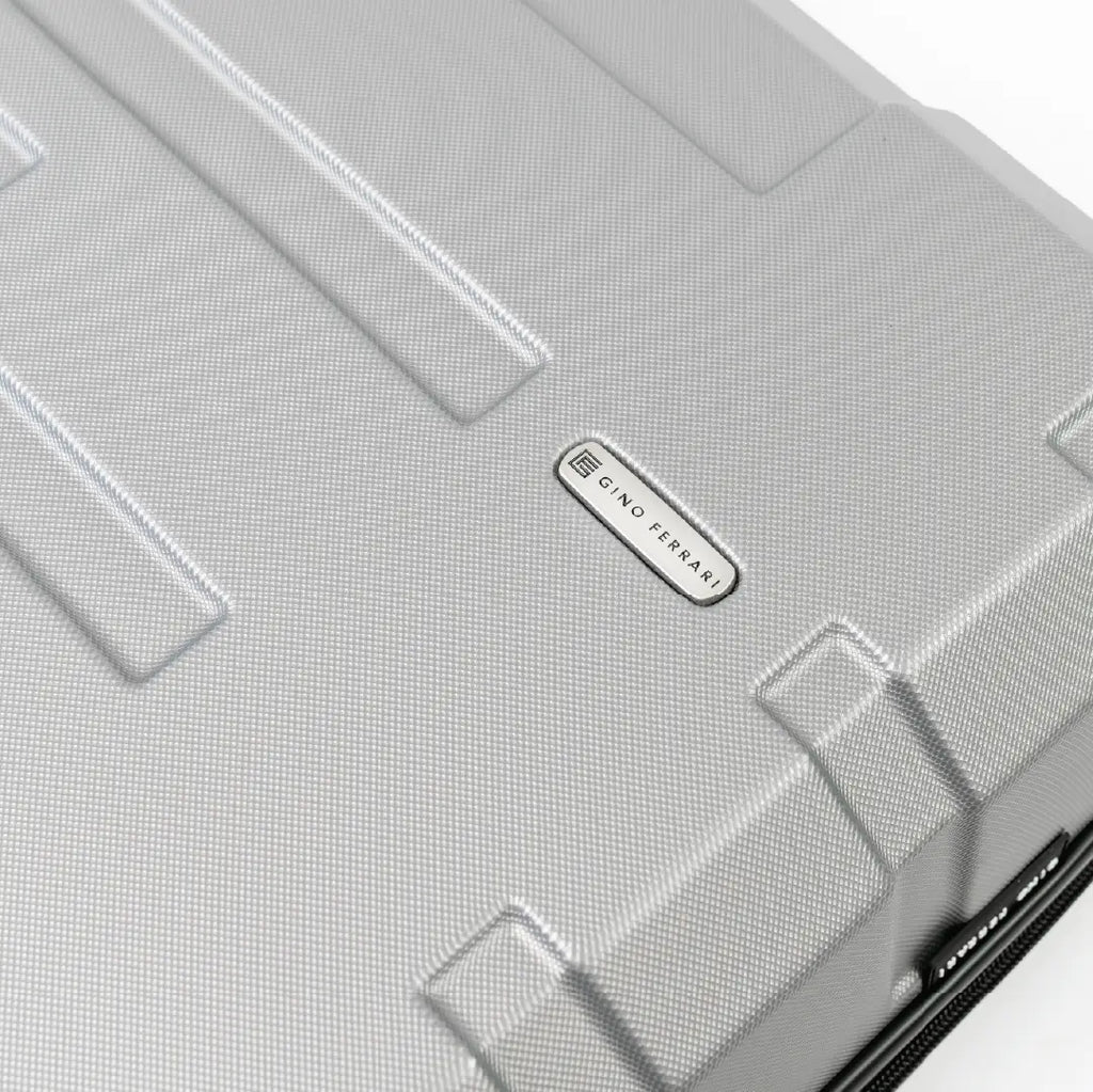 Close-up of a silver suitcase with a brand logo on a white background