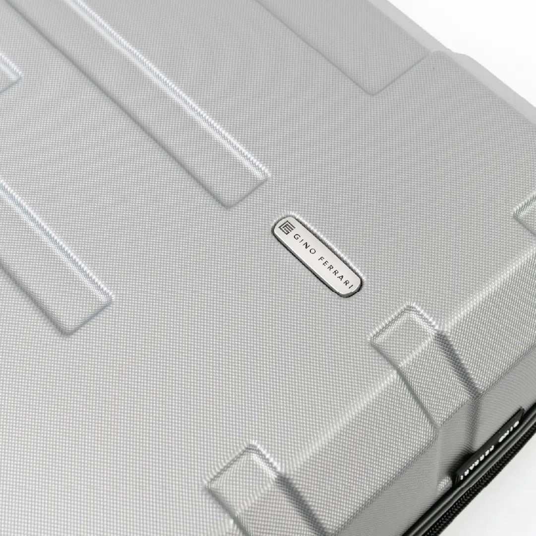 Close-up of a silver suitcase with a brand logo on a white background
