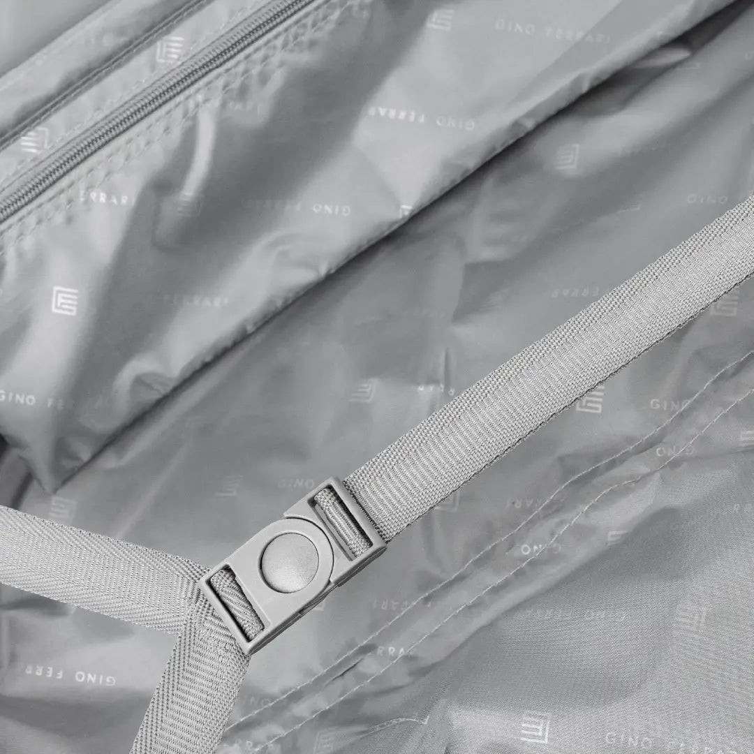 Close-up of a suitcase with a strap and buckle, featuring the brand.