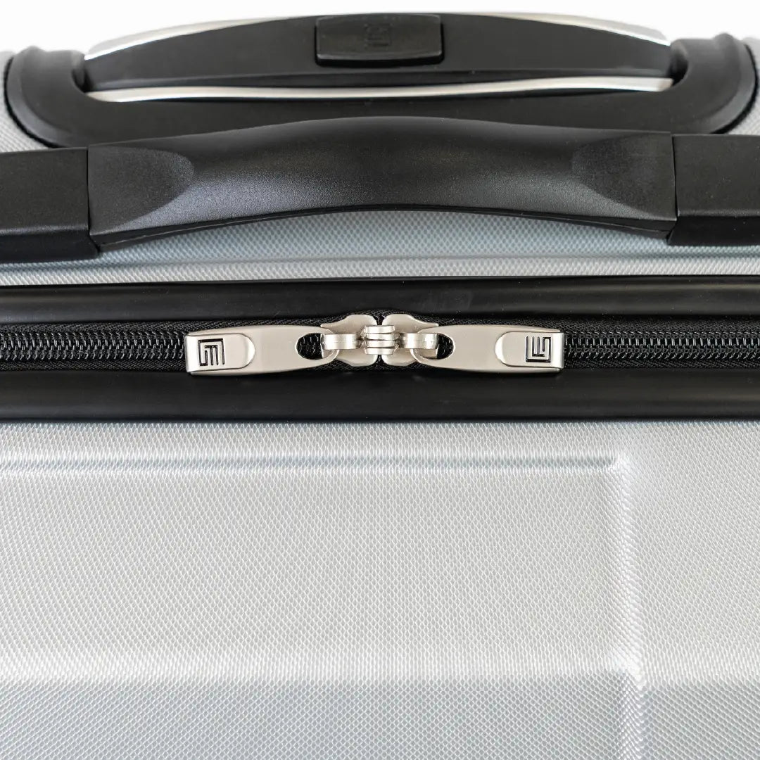 Close-up of a silver suitcase with a black handle and zipper.