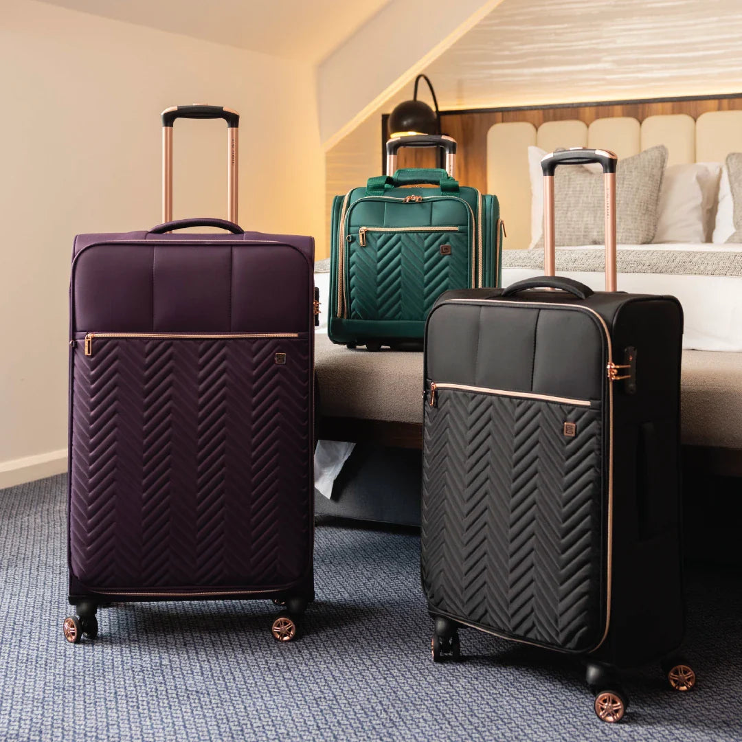 Three suitcases of different colors in a bedroom setting