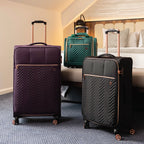 Three suitcases of different colors in a bedroom setting