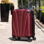 Red suitcase on wheels with a blurred outdoor background