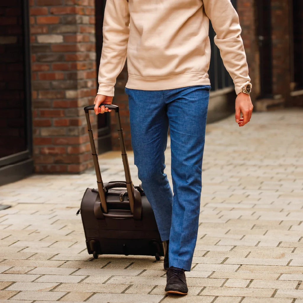 Person pulling a suitcase on a brick pavement