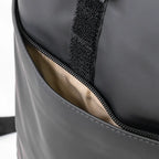 Close-up of a gray bag with black zipper and beige interior lining.