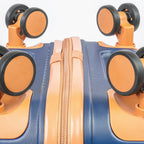 Close-up of a blue suitcase with orange handles and wheels on a light gray background
