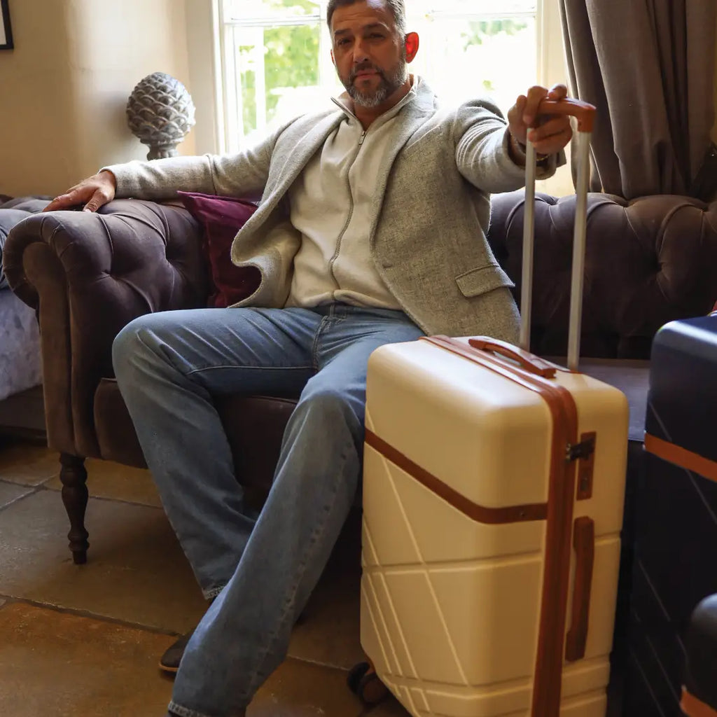 Man sitting on a couch with a suitcase in a living room setting