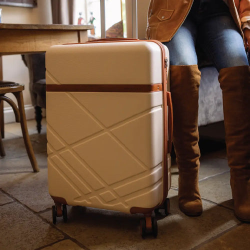 Beige suitcase with a person wearing brown boots in a room setting