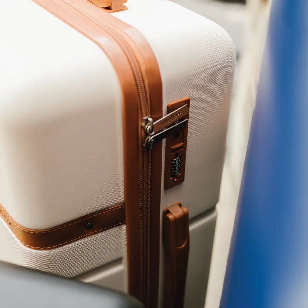 Beige suitcase with brown straps on a chair