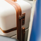 Beige suitcase with brown straps on a chair